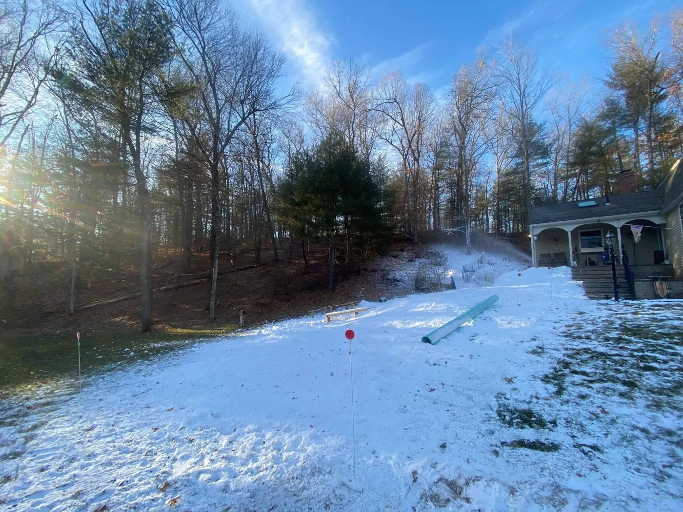 A snowgun throwing snow down a hill toward the house.