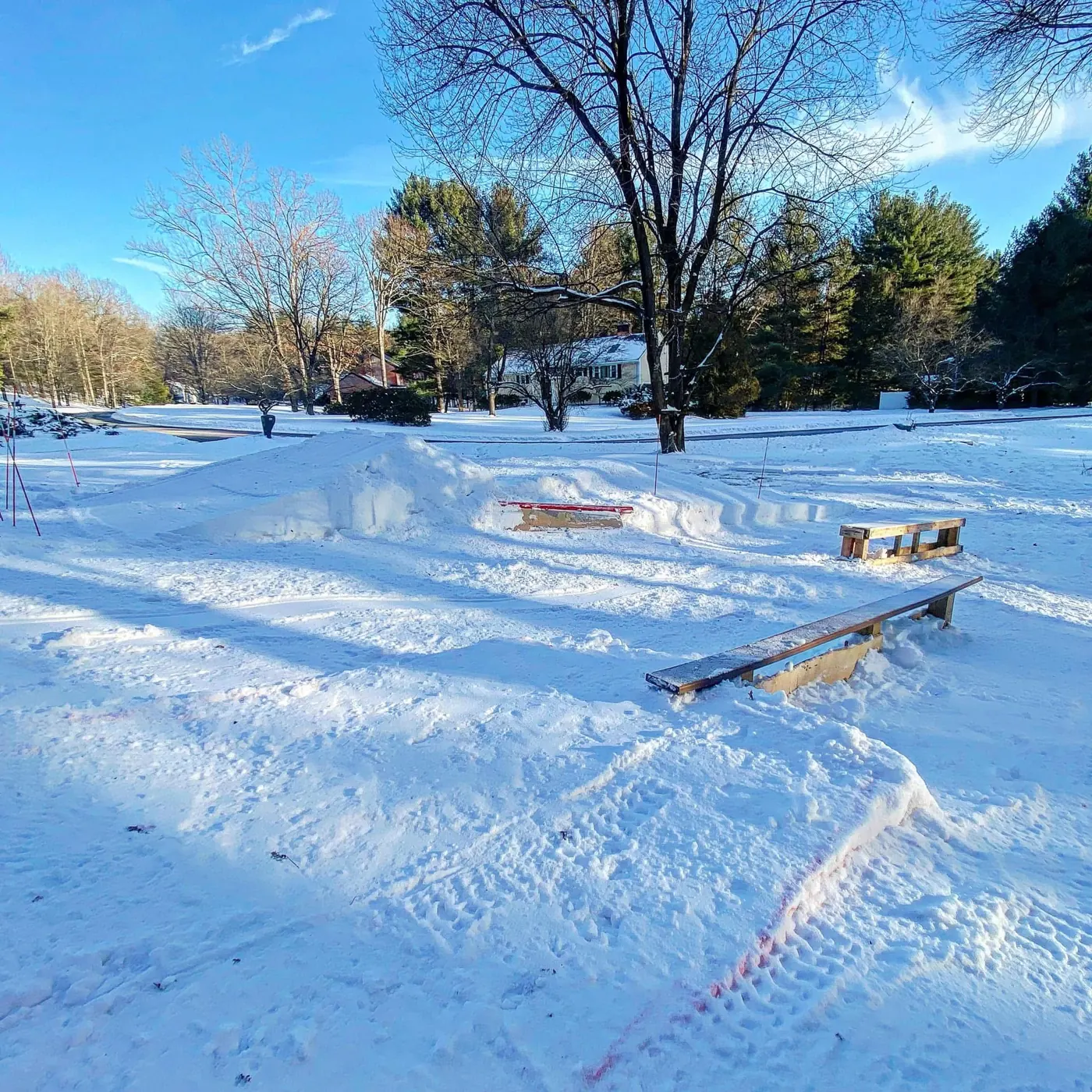 A sunny yard covered in snow with rails and a box.