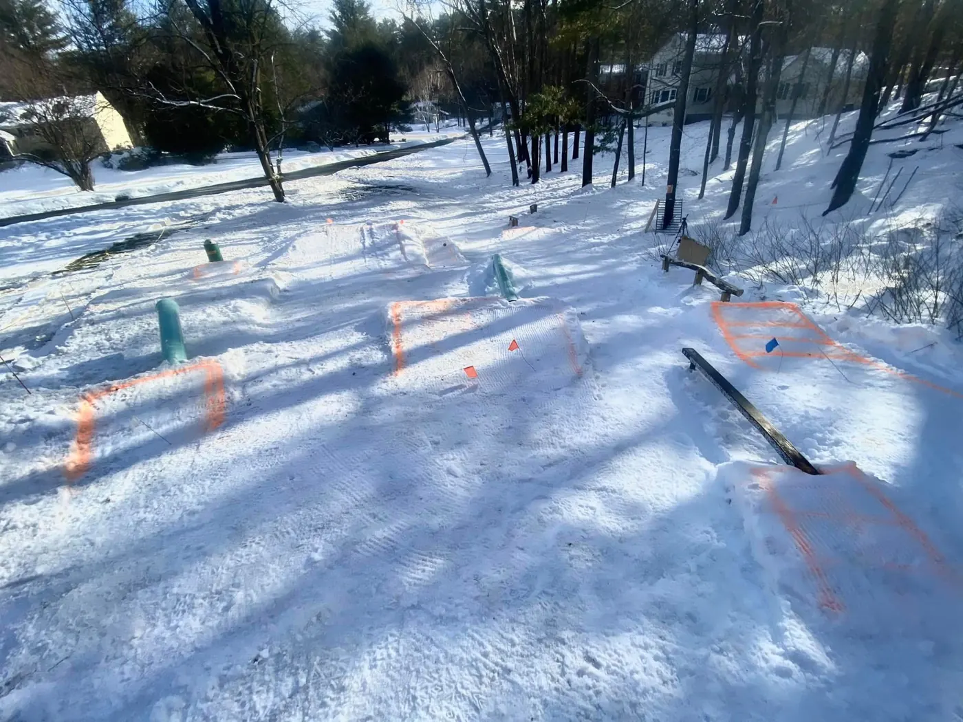 Rails and boxes on snow in a shaded yard.