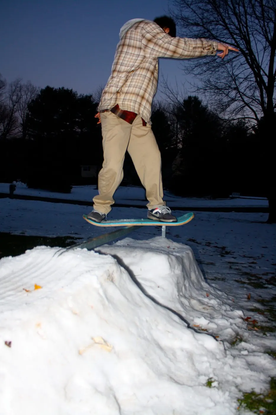 A snowboarder pressing a rail at dusk.