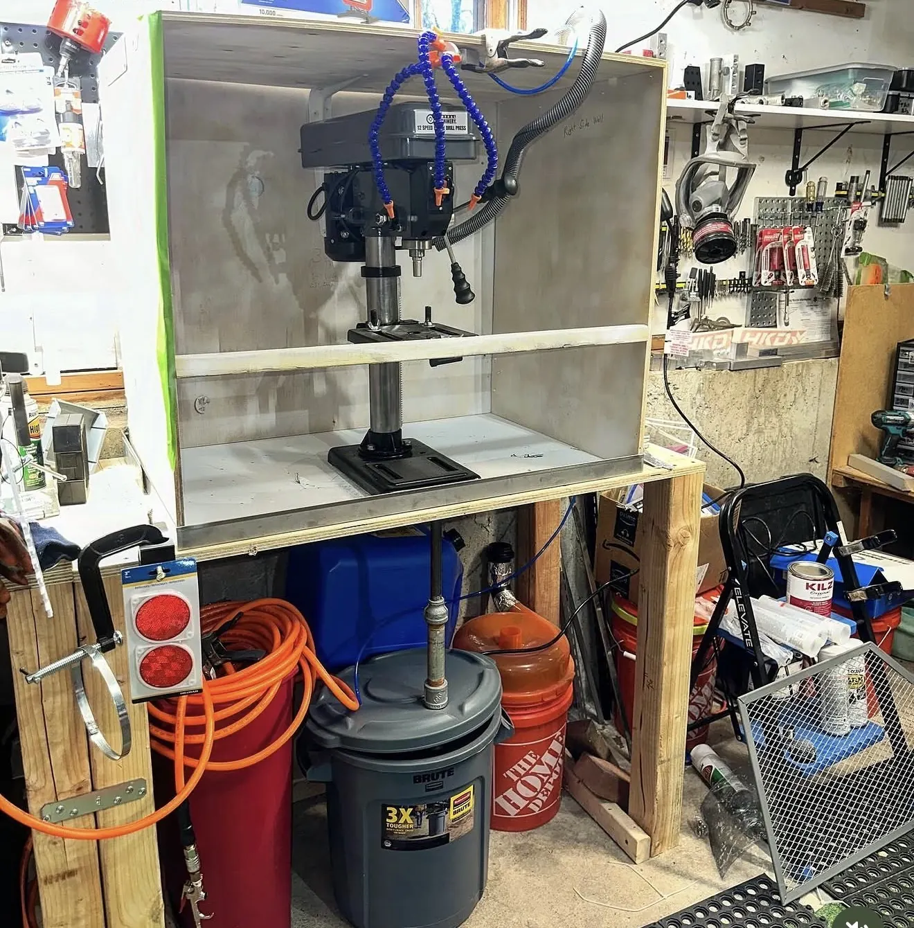 A drill press inside an enclosed cabinet in the shop.