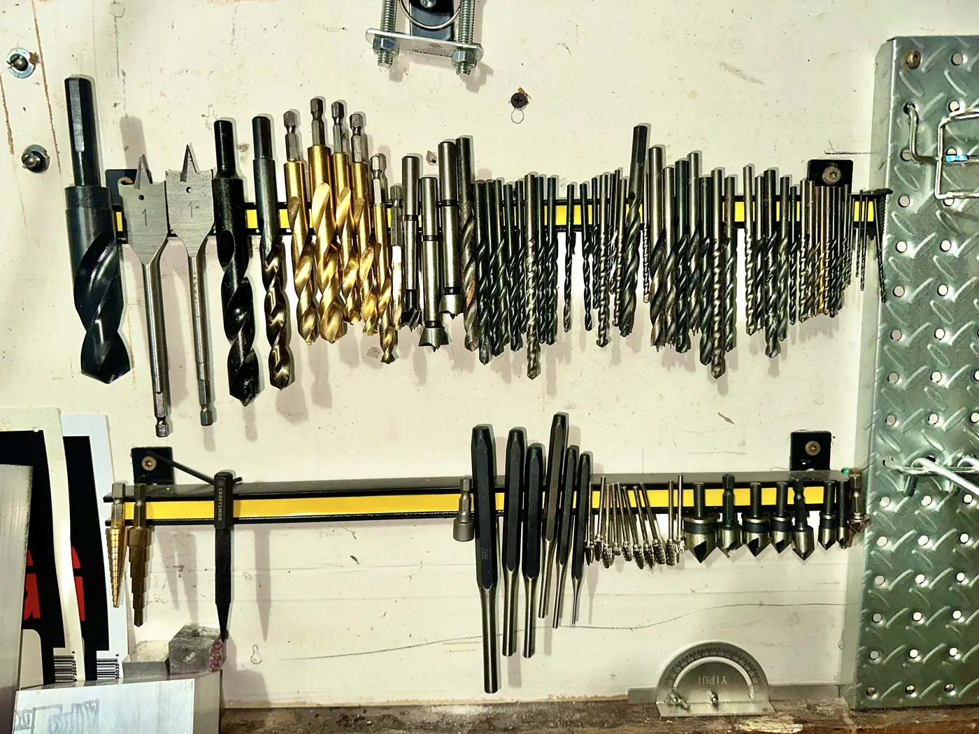 A wall rack of drill bits sorted by size.