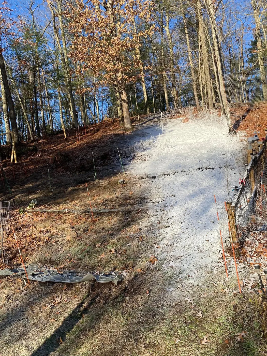 A strip of made snow running down through the woods.