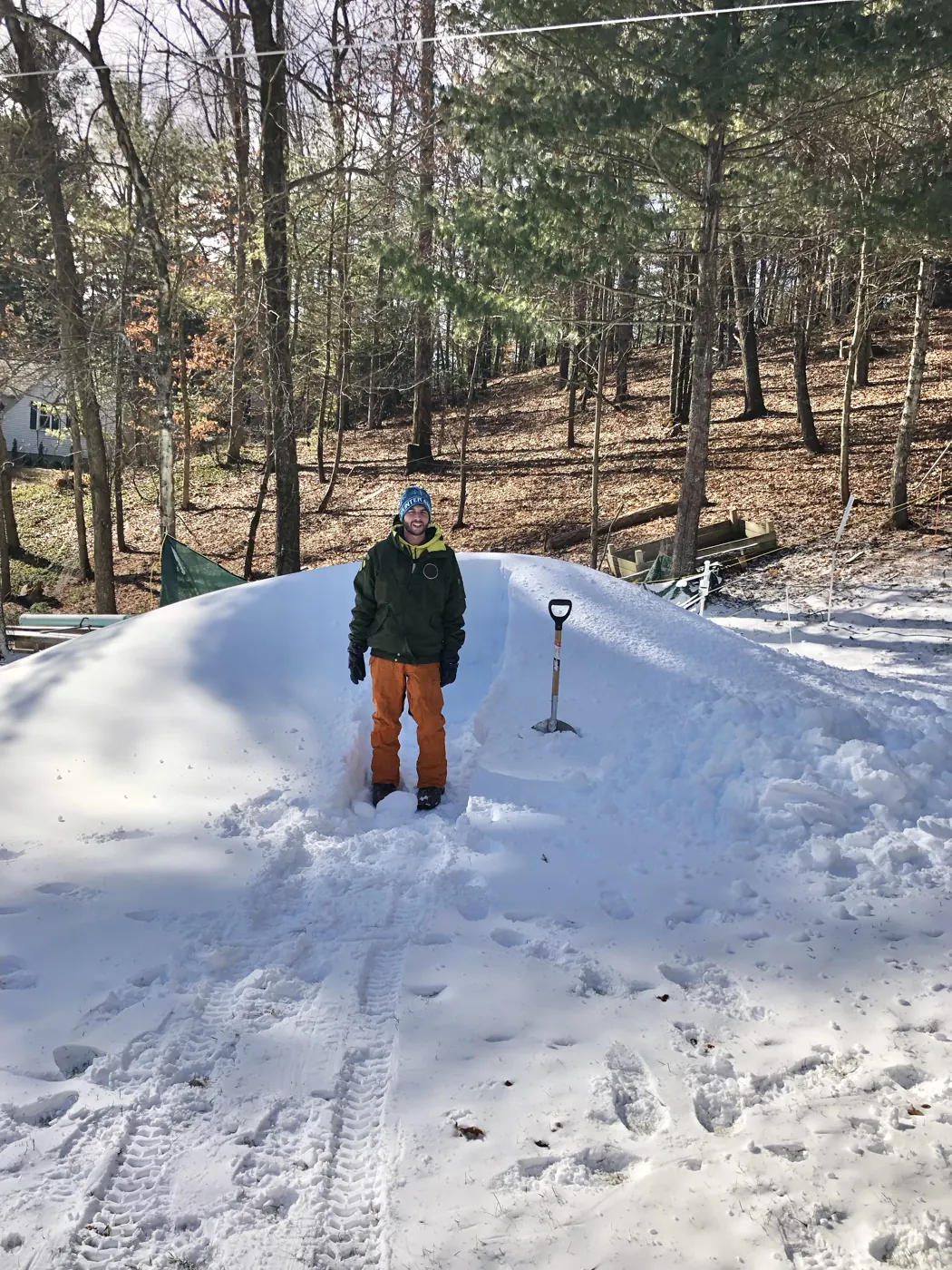A person standing on top of a big pile of snow.