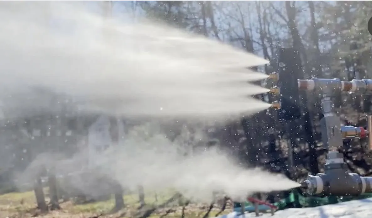 Several nozzles throwing fans of spray in the woods.