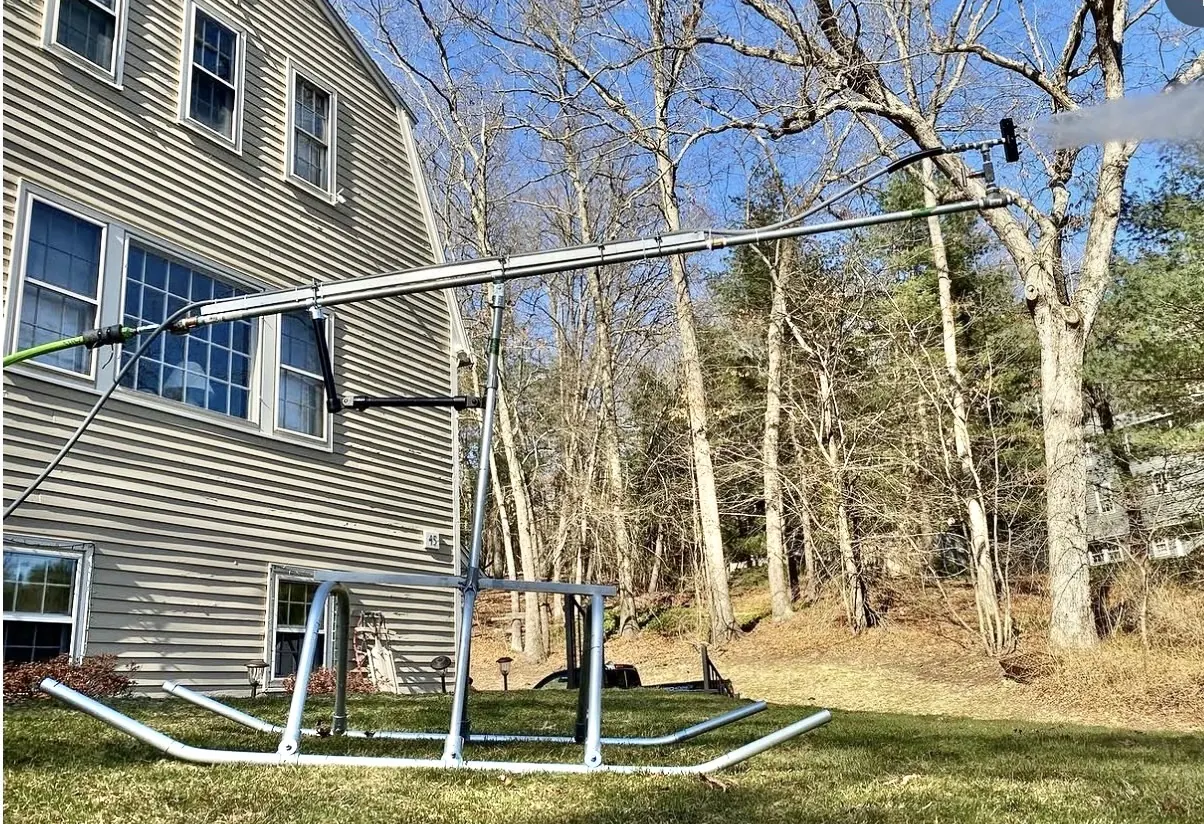 A long boom snowgun on a pipe skid frame next to the house.